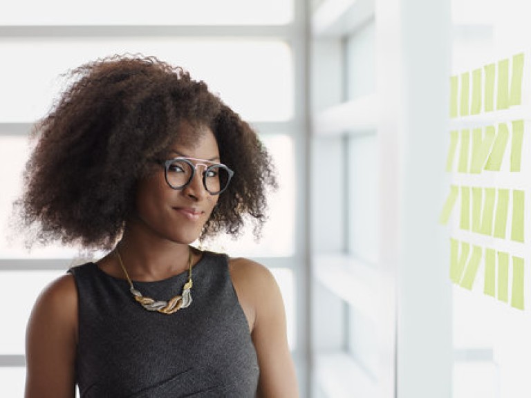 Portrait of a smiling business woman with an afro in bright glass office